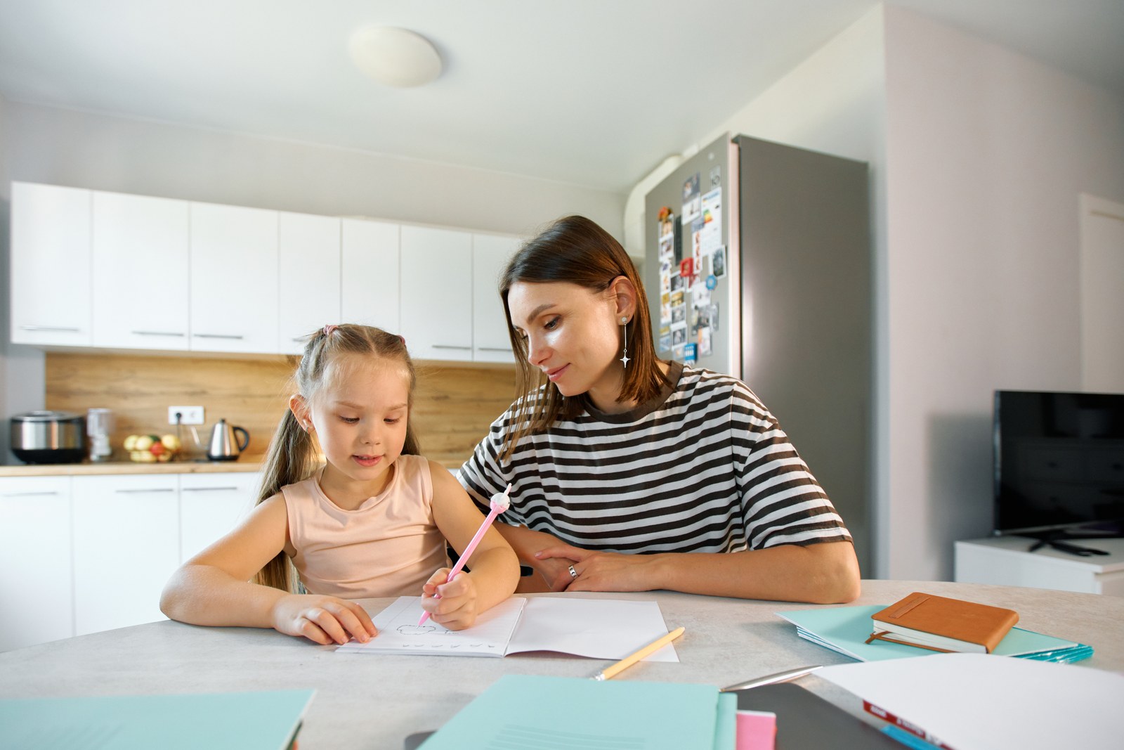 Une mère accompagne sa fille dans ses devoirs.